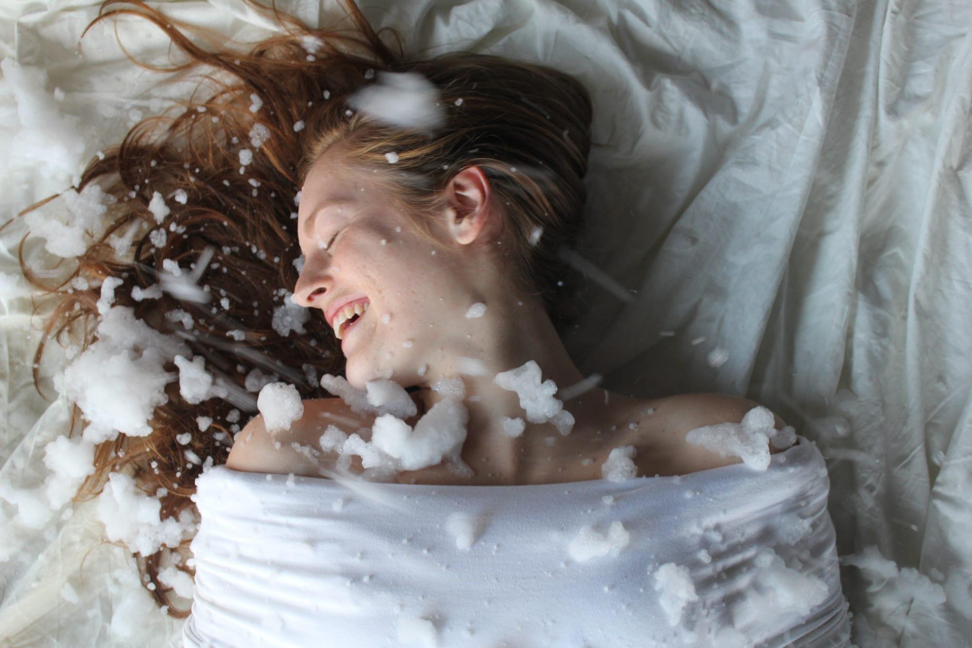 Una donna distesa su un tessuto bianco tra fiocchi di neve scenografica.