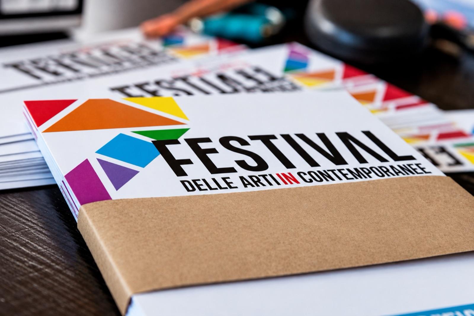 Copie del programma del festival impilate su un tavolo, con la copertina a triangoli colorati.